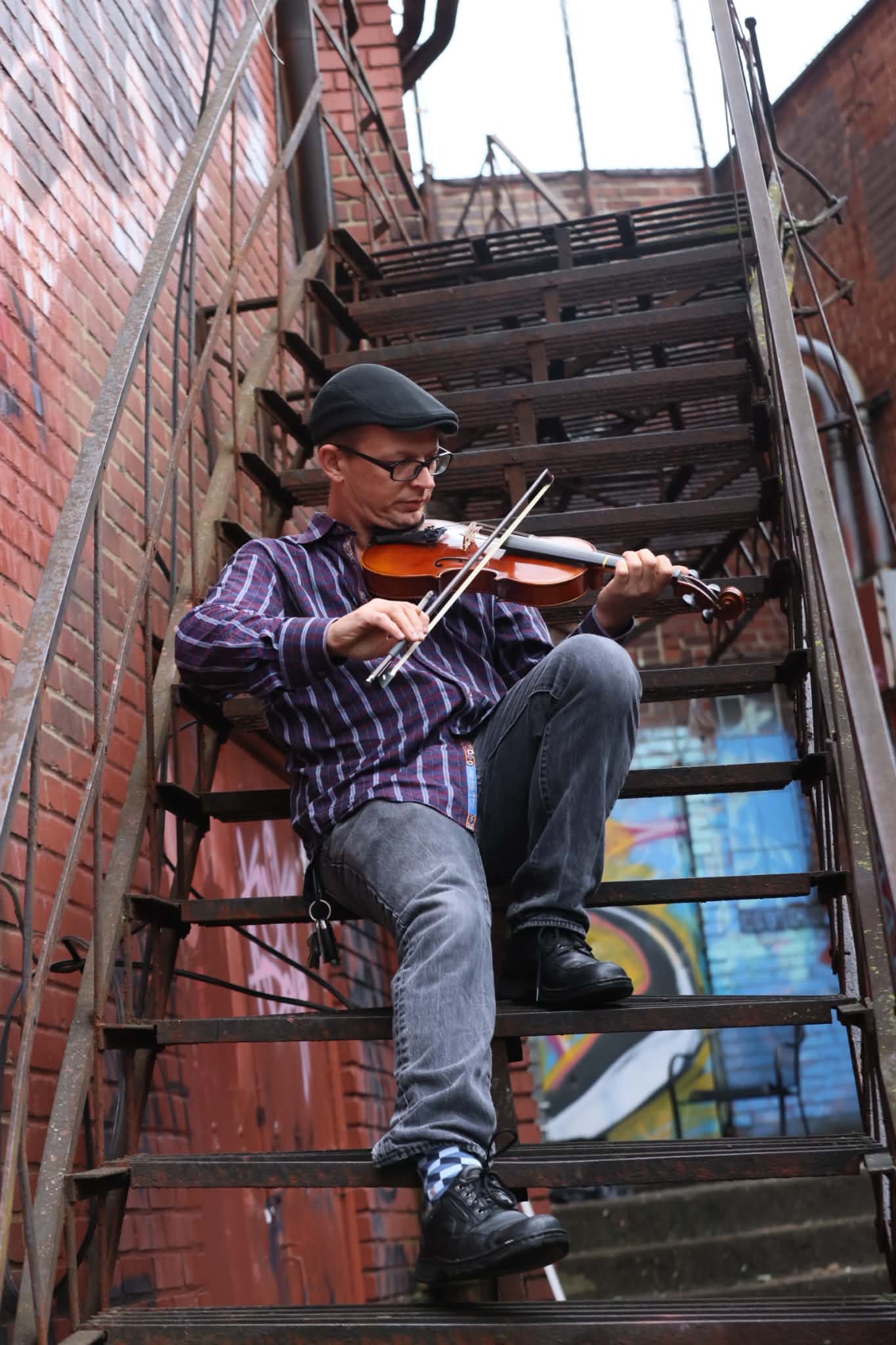 Mike’s Wilson playing violin on a brick stairway